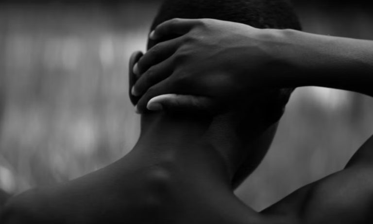 A still from Songbirds showing a boy with a hand on his head