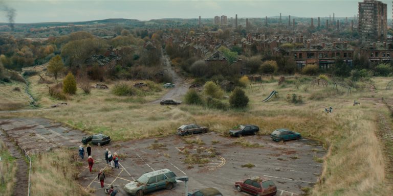 People walking by cars with a derelict building in the background
