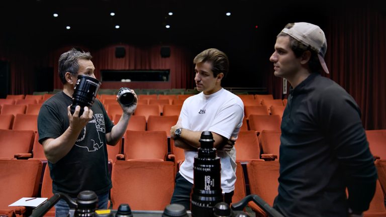 One person holding lenses with two others talking to them