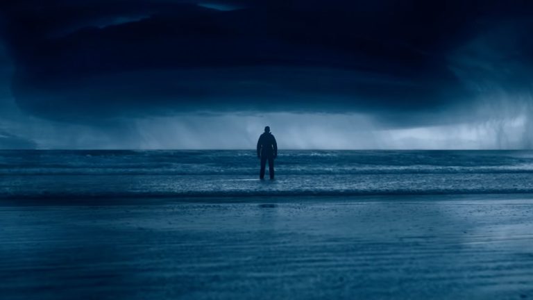 A man standing in the sea in the dark